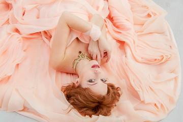 Portrait of a beautiful girl in a beige peach dress in the Studio