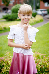 Fototapeta premium Portrait of beautiful little girl in a white blouse with a pink skirt in the Park