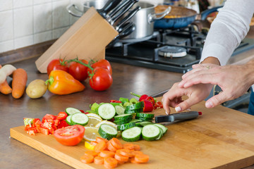man and woman in the kitchen, hands reach for the knife
