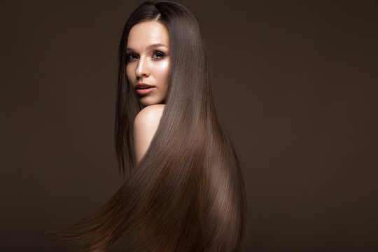 Fototapeta Beautiful brunette girl in move with a perfectly smooth hair, and classic make-up. Beauty face. Picture taken in the studio.