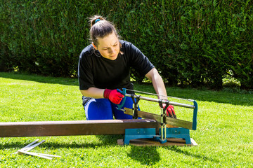 Girl is sawing a wooden beam in the garden