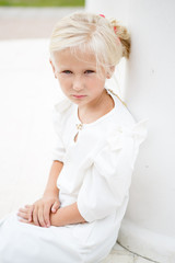 Naklejka premium Portrait of beautiful little girl in a white dress near the columns