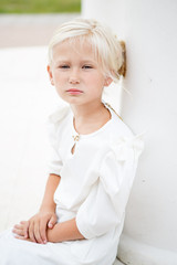 Portrait of beautiful little girl in a white dress near the columns