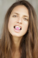 Beautiful woman holding heart with teeth in her mouth.