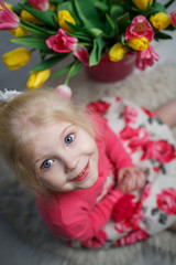 Portrait of a beautiful little girl with flowers on background of brick wall