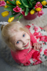 Portrait of a beautiful little girl with flowers on background of brick wall