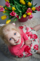 Portrait of a beautiful little girl with flowers on background of brick wall