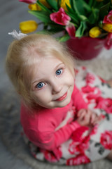 Portrait of a beautiful little girl with flowers on background of brick wall