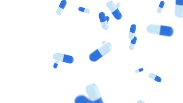 Pills falling on white background in slow motion