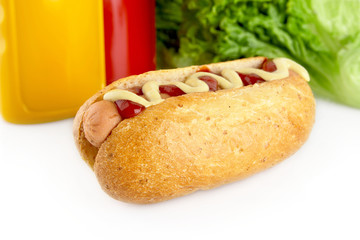 Hot dog with ketchup and mustard with salad in the background