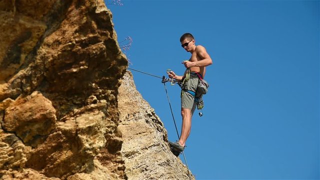 Extreme Climber Hanging On A Rope Resting His Feet Into Rock