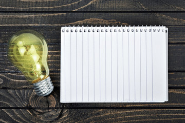 Notepad and bulb on table