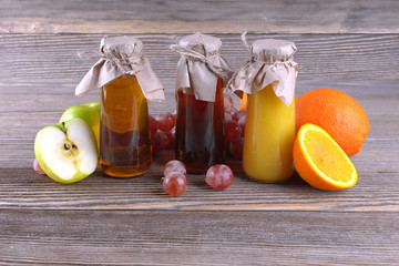 Three bottles of fruit juice on a background of wood