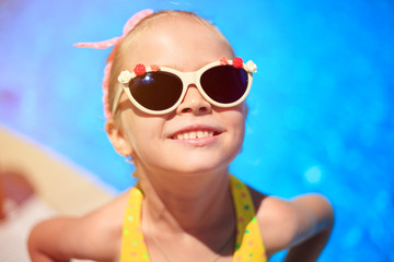 Cute smiling little girl near swimming pool. summer vacation concept