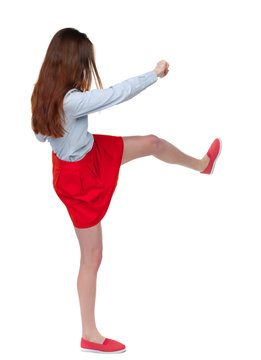 skinny woman funny fights waving his arms and legs. Isolated over white background. Long-haired brunette in red skirt swung a leg.