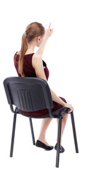 back view of young beautiful  woman sitting on chair and pointing.  girl  watching. Rear view people collection. A girl in a burgundy dress sitting on a chair finger pointing.