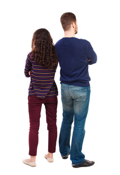 Back view of young embracing couple (man and woman) hug and look into the distance. backside view of person.  Isolated over white background. Swarthy girl and a bearded man standing back to back.