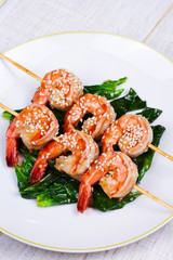 Skewered Sesame Shrimp on Spinach in White Plate. View from above, top studio shot