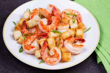 Shrimp with crispy croutons and scallions in white plate