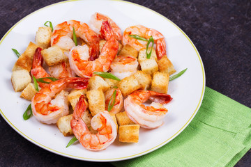 Fototapeta na wymiar Shrimp with crispy croutons and scallions in white plate