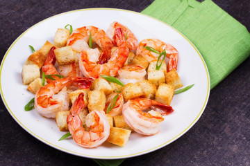 Shrimp with crispy croutons and scallions in white plate