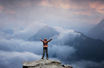 Man standing on the top of the mountain over clouds