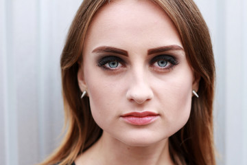 Obraz premium Young pretty woman portrait. Outdoor portrait of a young cute blond woman with a long hair Gray background. Beautiful face eyes and lips. Charming smile