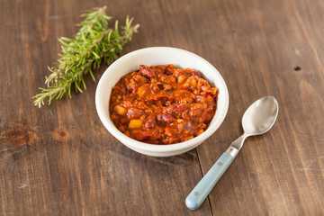 A Hot Bowl Of Spicy Organic Vegetarian Chili With Melted Cheese On A Distressed Wood Country Table.