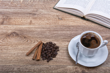 A cup of coffee and cinnamon with a book