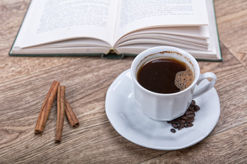 A cup of coffee and cinnamon with a book