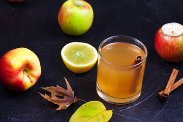 Cider glass with apples, lemon and cinnamon on black background