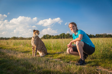 Young woman on a green meadow in summer walking cheetah © edojob