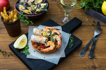 Italian food. Bruschetta with squid and prawns, tomatoes, parsley.