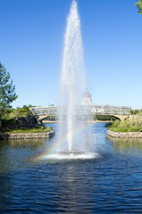 Early morning  rainbow in a fountain in Wascana Park in Regina Saskatchewan. In the background is the Saskatchewan Legislature and a walking bridge.