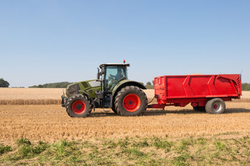 Tractor with a red trailer carrying grain