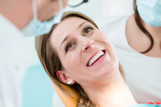Frau mit gesundem Lächeln beim Zahnarzt nach erfolgreicher Behandlung