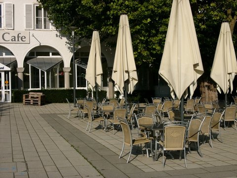 Café mit Tischen, Stühlen und Sonnenschirm in Beige und Naturfarben bei Sonnenschein am Kurpark in Bad Salzuflen bei Herford in Ostwestfalen-Lippe