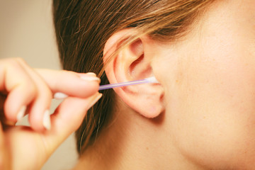 Woman cleaning ear with cotton swabs closeup
