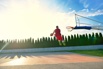 A young basketball player flying towards the rim for a slam dunk.