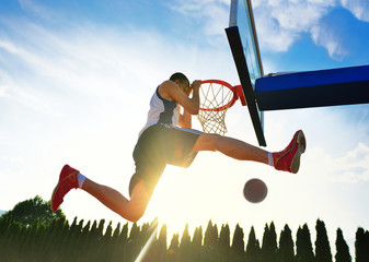Naklejka premium Street basketball player performing power slum dunk.