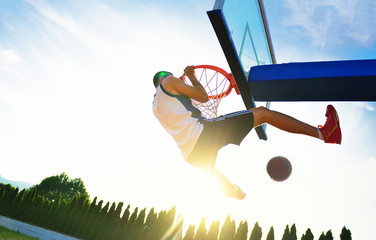 Street basketball player performing power slum dunk.