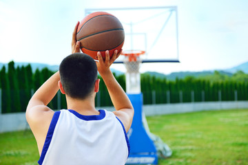 Rear view of a basketball player, shooting at basket outdoor