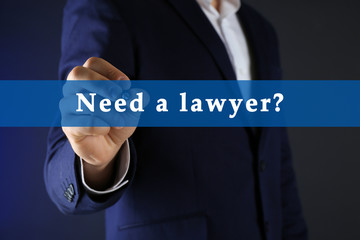 Businessman in suit with pen on dark background. Need a lawyer?