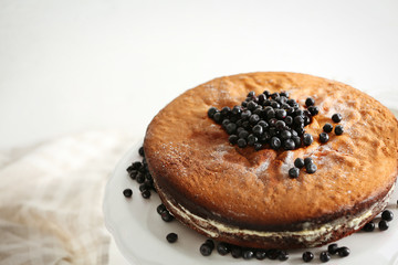 Delicious cake decorated with blueberry on white stand