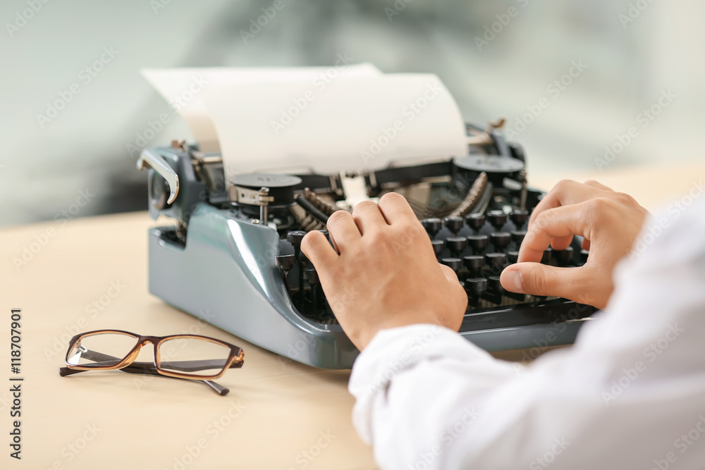 Fototapete man working on retro typewriter at desk