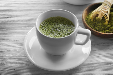 Cup of fresh matcha tea on wooden background