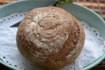 black bread round shape in a blue bowl with white tablecloth and a knife in the background