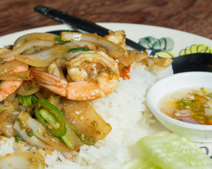 Spicy fried shrimp with basil leaves on the wood table.
