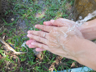 Hands washing under stream of water from faucet