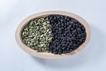 Aronia and Pumkin seeds in wooden bowl